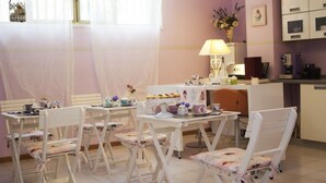 Un coin repas accueillant, avec des chaises pliantes blanches et une table dressée avec différents plats et une théière.