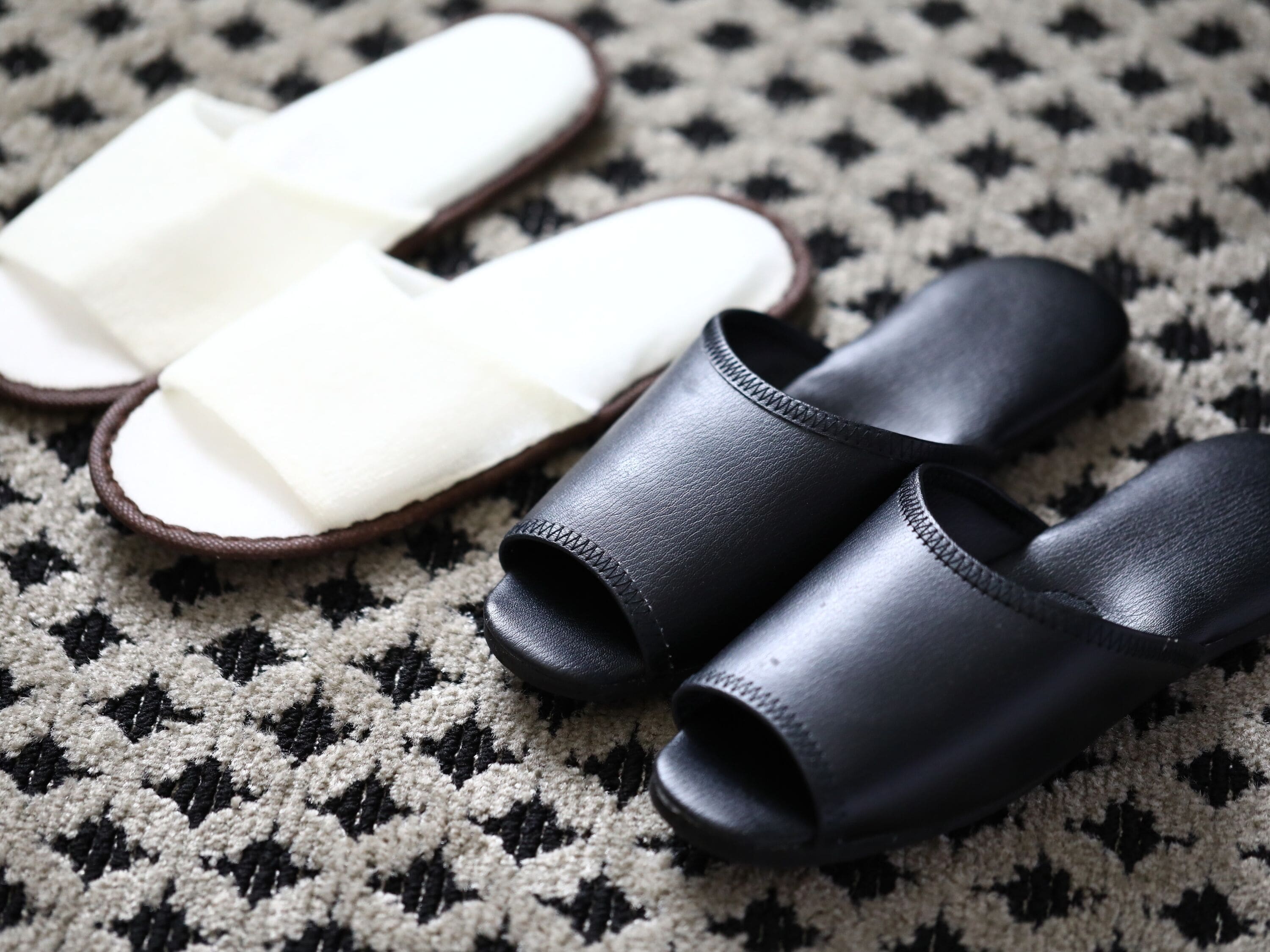 A pair of black and white slippers on a patterned rug.