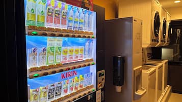 A vending machine with various drinks and a washing machine in the background.