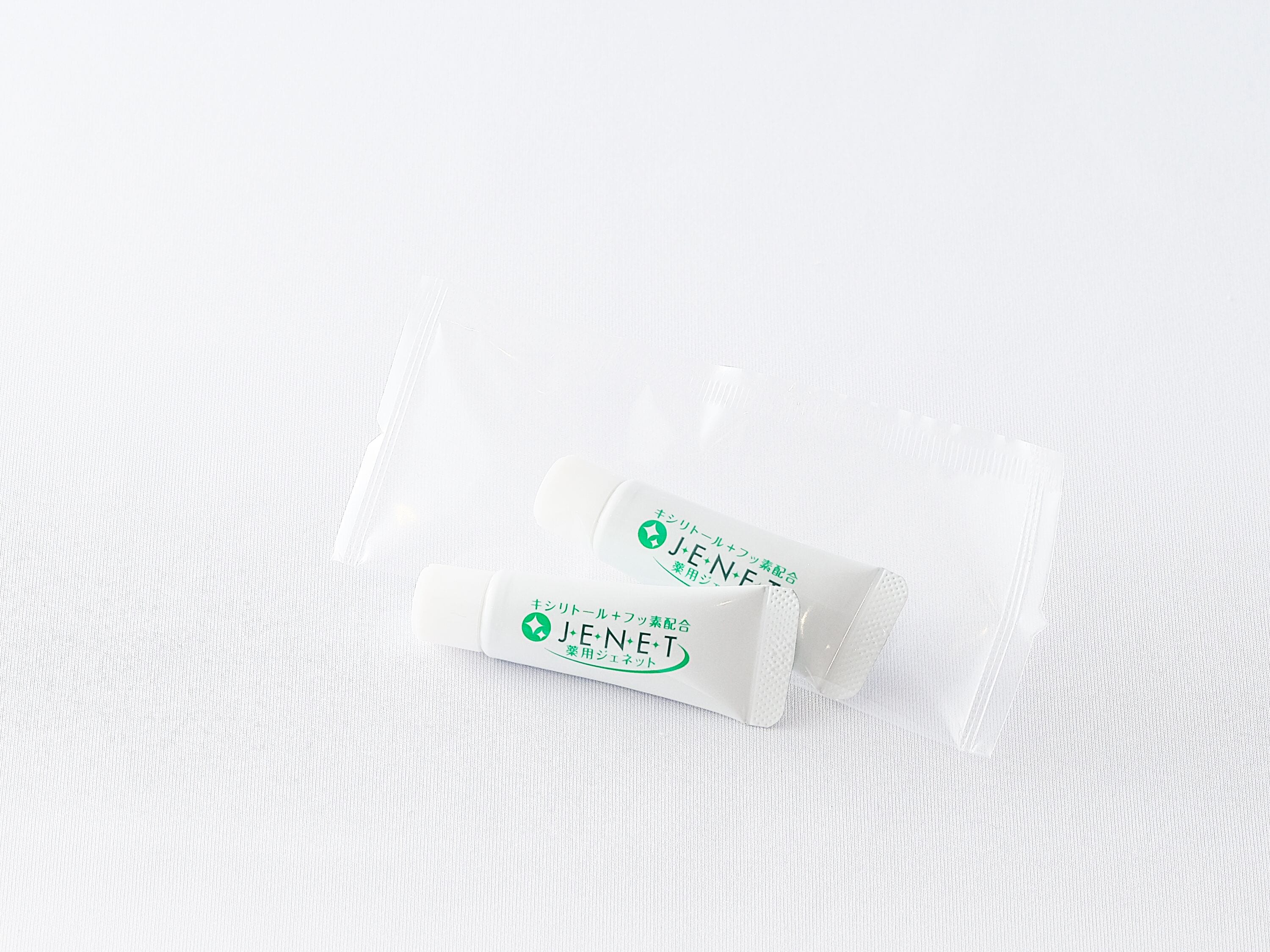 Two white sachets with green and black text on a white textured background.