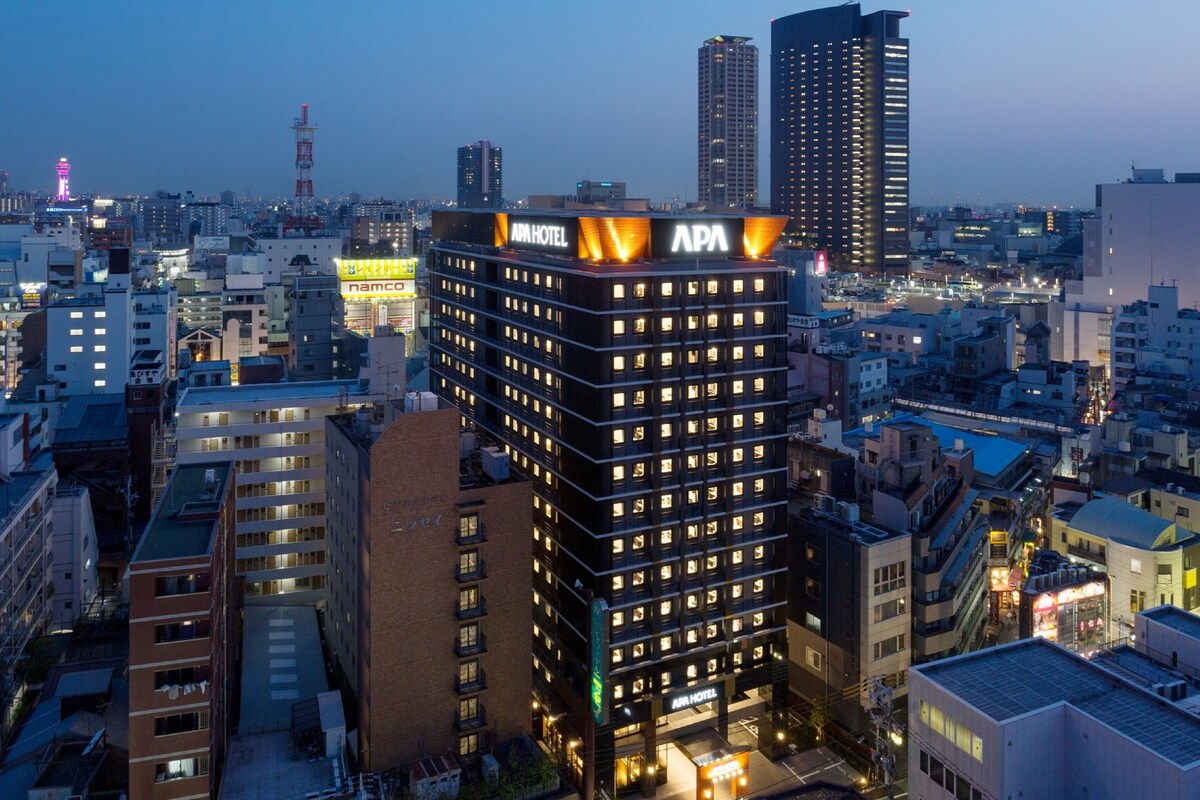 A high-rise building with multiple floors, featuring a prominent 'APA' sign on the top.