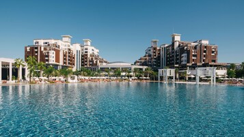 Ein Hotel mit großem Pool, mehreren Gebäuden und Palmen.