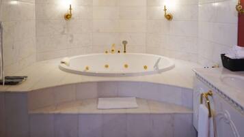 A bathroom with a freestanding bathtub, marble walls, and gold fixtures.