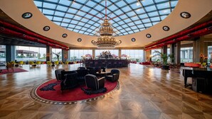 A spacious lobby with a high ceiling, a grand chandelier, and a central bar area. - Selectum Luxury Resort (Serik)