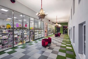 Ein Korridor mit Glasvitrinen, gefüllt mit Spielzeug und Stofftieren, mit Schachbrettfußboden und roten Samtstühlen.