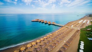A beach resort with a pier extending into the sea, rows of sunbeds, and a clear sky. - Selectum Luxury Resort (Serik)