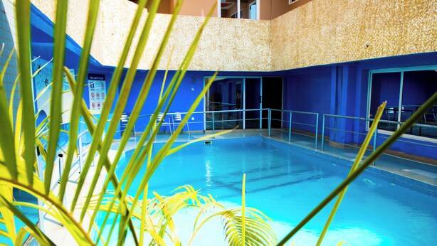 Una piscina con agua cristalina azul, rodeada de paredes azules y un suelo con mosaicos.