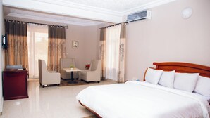 Habitación de hotel con una cama grande, un escritorio, una silla y una pequeña mesa con un florero.