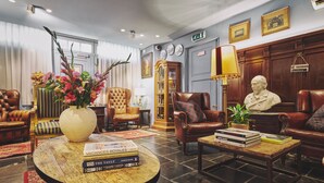 Una sala de estar bien amoblada con sofás de cuero, una mesa de centro con libros, un jarrón con flores y una estatua.