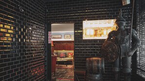 Una habitación con pared de ladrillo, un banco de madera y una estatua.