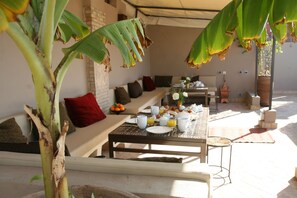 A breakfast setup with a table, chairs, and a bench. - Riad Vanilla Sma (Marrakech)