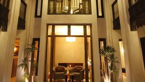 A hotel lobby with a central water feature, a chandelier, and a seating area with a sofa and armchairs. - Riad Vanilla Sma (Marrakech)