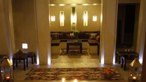 A lobby with a central seating area, a decorative rug, and a candelabra with candles. - Riad Vanilla Sma (Marrakech)