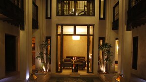 A lobby with a central seating area, a water feature, and two potted plants. - Riad Vanilla Sma (Marrakech)