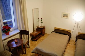 Een compacte, nette kamer met een enkel bed, een stoel, een klein tafeltje, een spiegel en een bedlampje.