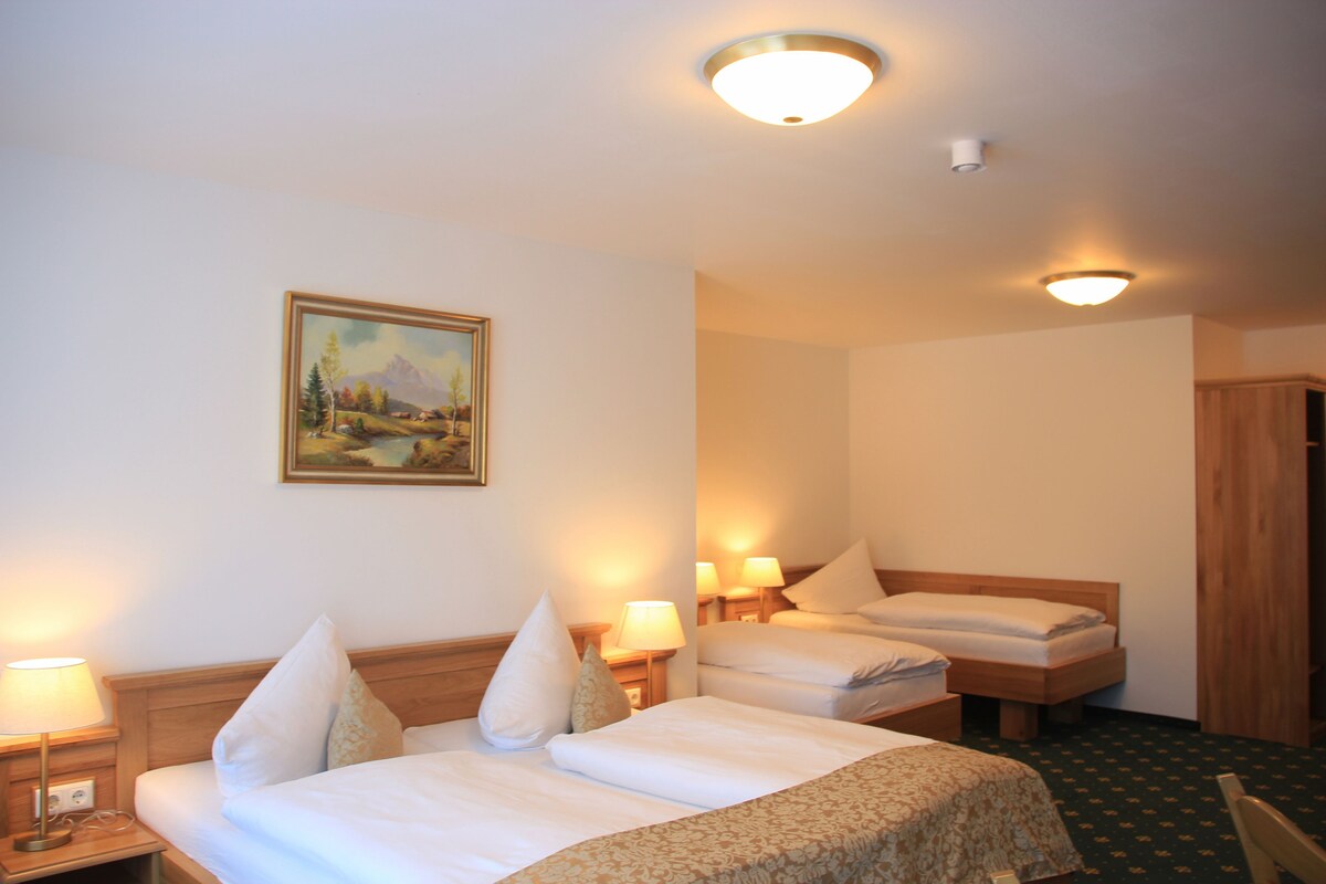 A hotel room with two beds, a painting on the wall, and a ceiling light fixture.
