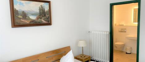 Hotellihuone, jossa on sänky, taulu, lamppu ja näkymä kylpyhuoneeseen.