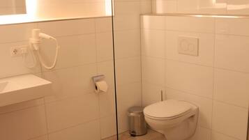 Un baño moderno con cabina de ducha de vidrio, un lavabo blanco y un inodoro.