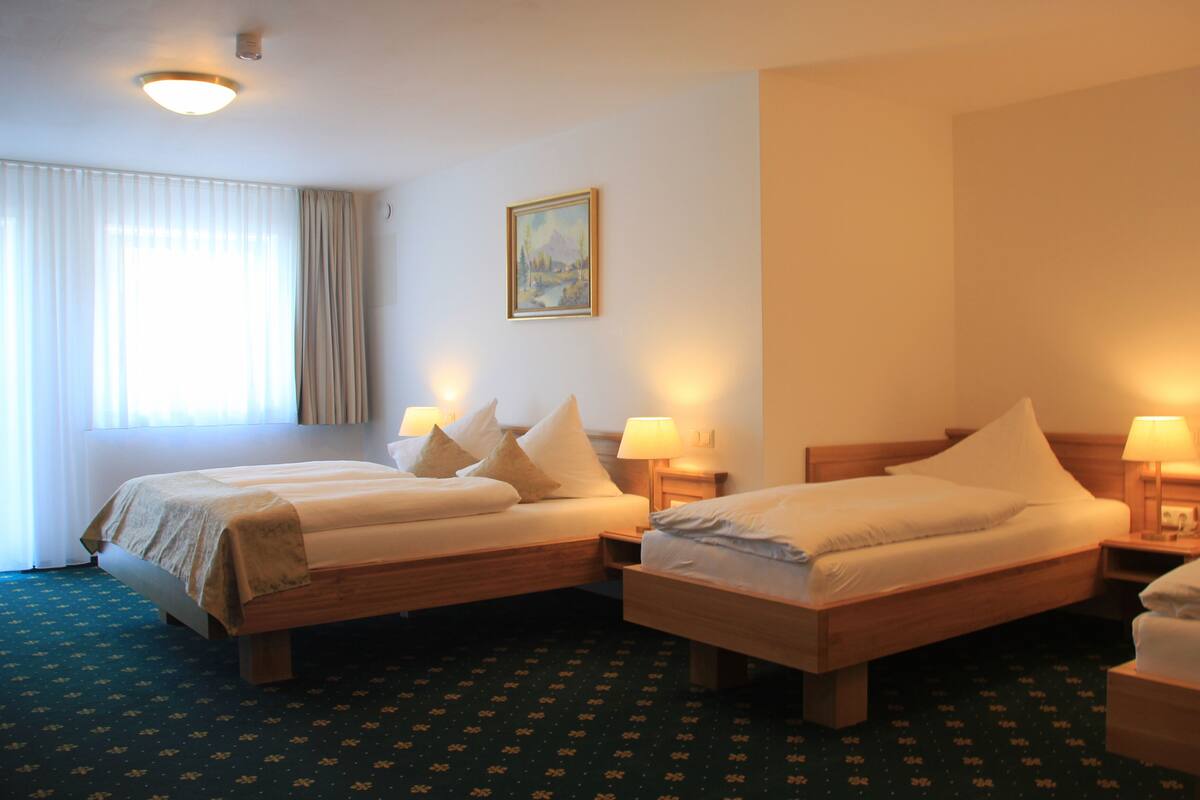 Una habitación de hotel con dos camas individuales, un cuadro en la pared y una ventana con cortinas.