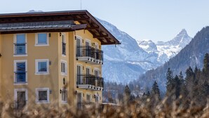 Un immeuble à plusieurs étages, doté de balcons, qui se dresse sur fond de montagnes.