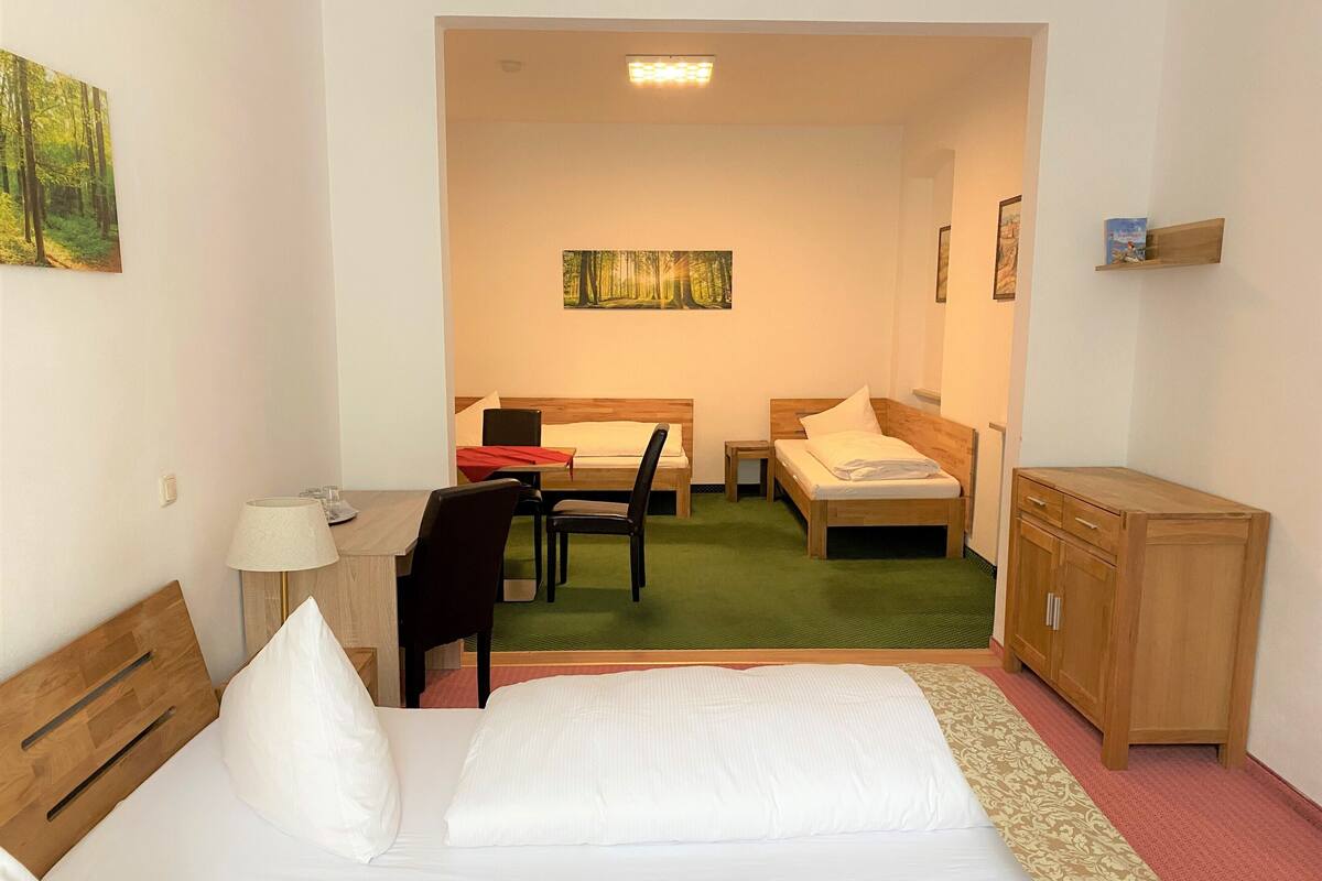 Una habitación de hotel con cama, escritorio, silla, mesita y armario.
