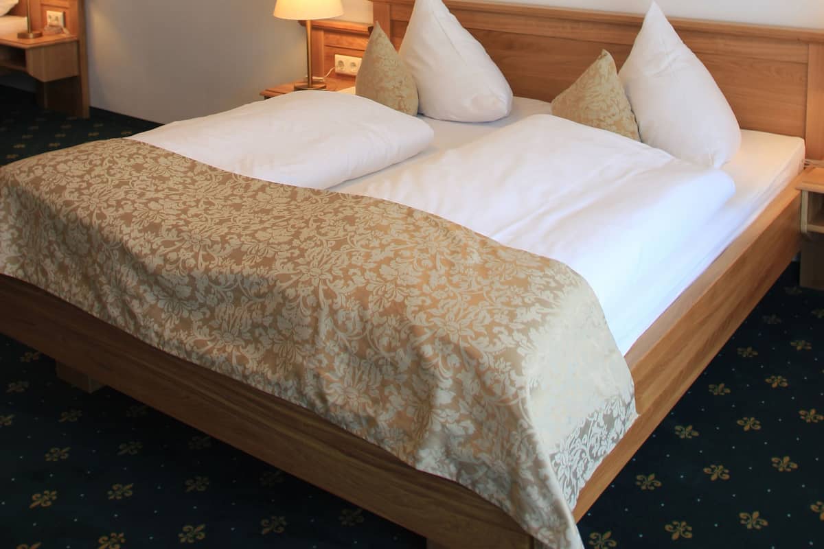 Una habitación de hotel con una cama grande, dos lámparas de noche, un cuadro en la pared y una luz en el techo.