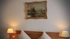 Une chambre d’hôtel comprenant un lit, deux tables de chevet, deux lampes et un tableau encadré représentant un paysage, accroché au mur.