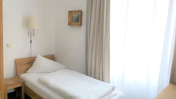 Una cama bien hecha con sábanas blancas en una habitación con cabecera de madera.