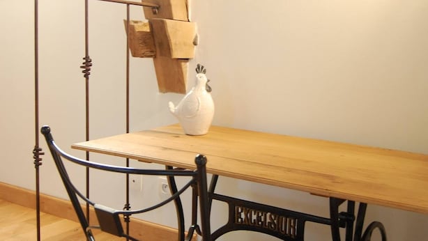A dining area with a wooden table and metal chair, a white vase on the table, and exposed wooden beams on the ceiling. - Ferme de Bellevue (Landes-le-Gaulois)