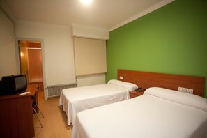 A hotel room with two single beds, a wooden desk with a television, and a green wall. - Pensión San Roque (Lugo)