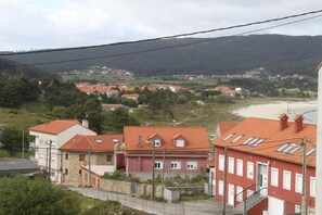 A residential area with houses featuring red-tiled roofs and a hillside in the background. - Pensión San Roque (Lugo)