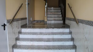 Uma escadaria de mármore com corrimãos, que leva a um andar superior.