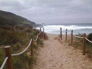 A sandy beach path with wooden posts and white ropes, leading to the ocean. - Pensión San Roque (Lugo)