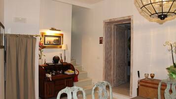 Un comedor con una mesa dispuesta para dos personas, una escalera y una puerta de madera.