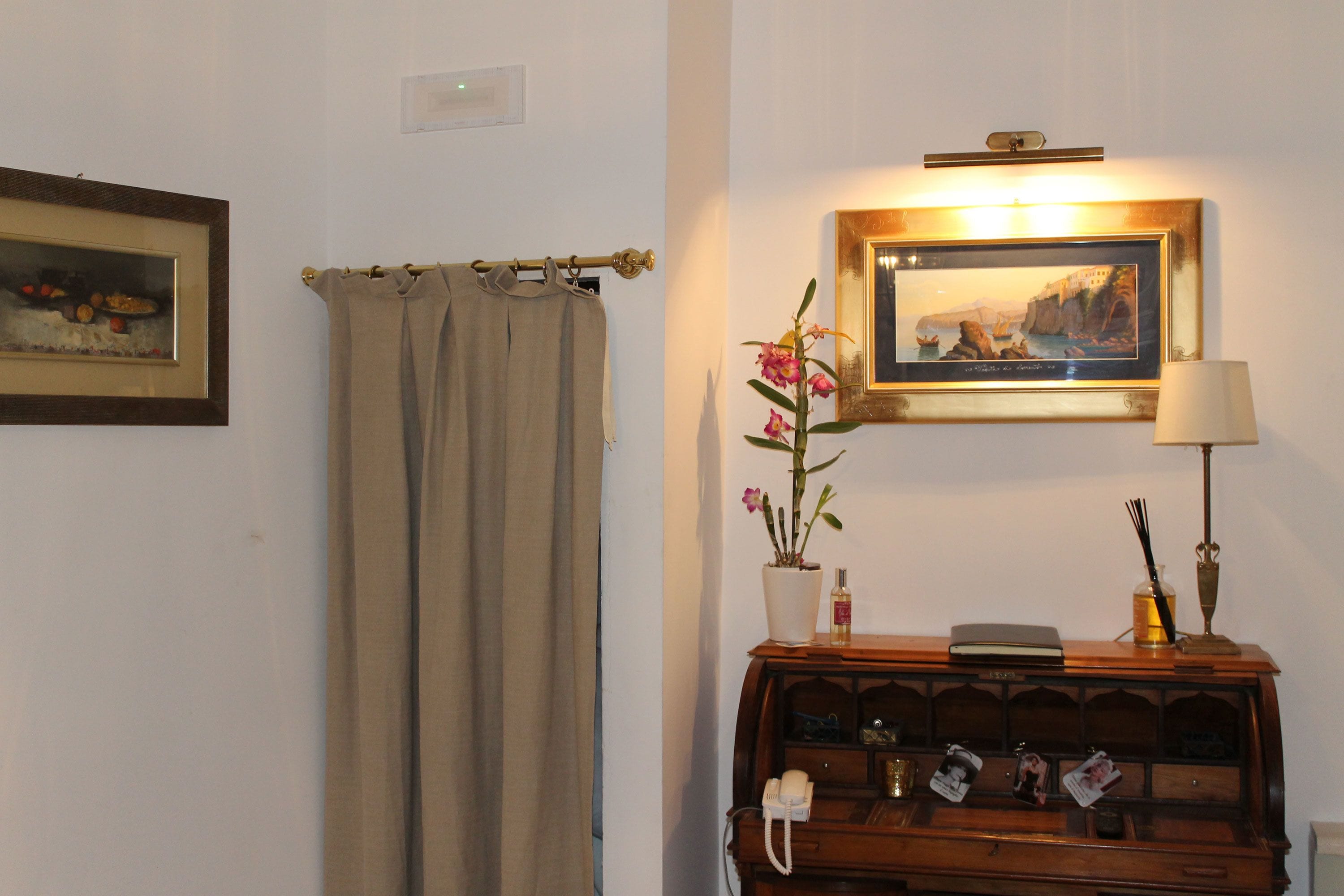 A bathroom with a beige towel, a framed painting, a lamp, and a wooden vanity with a mirror.