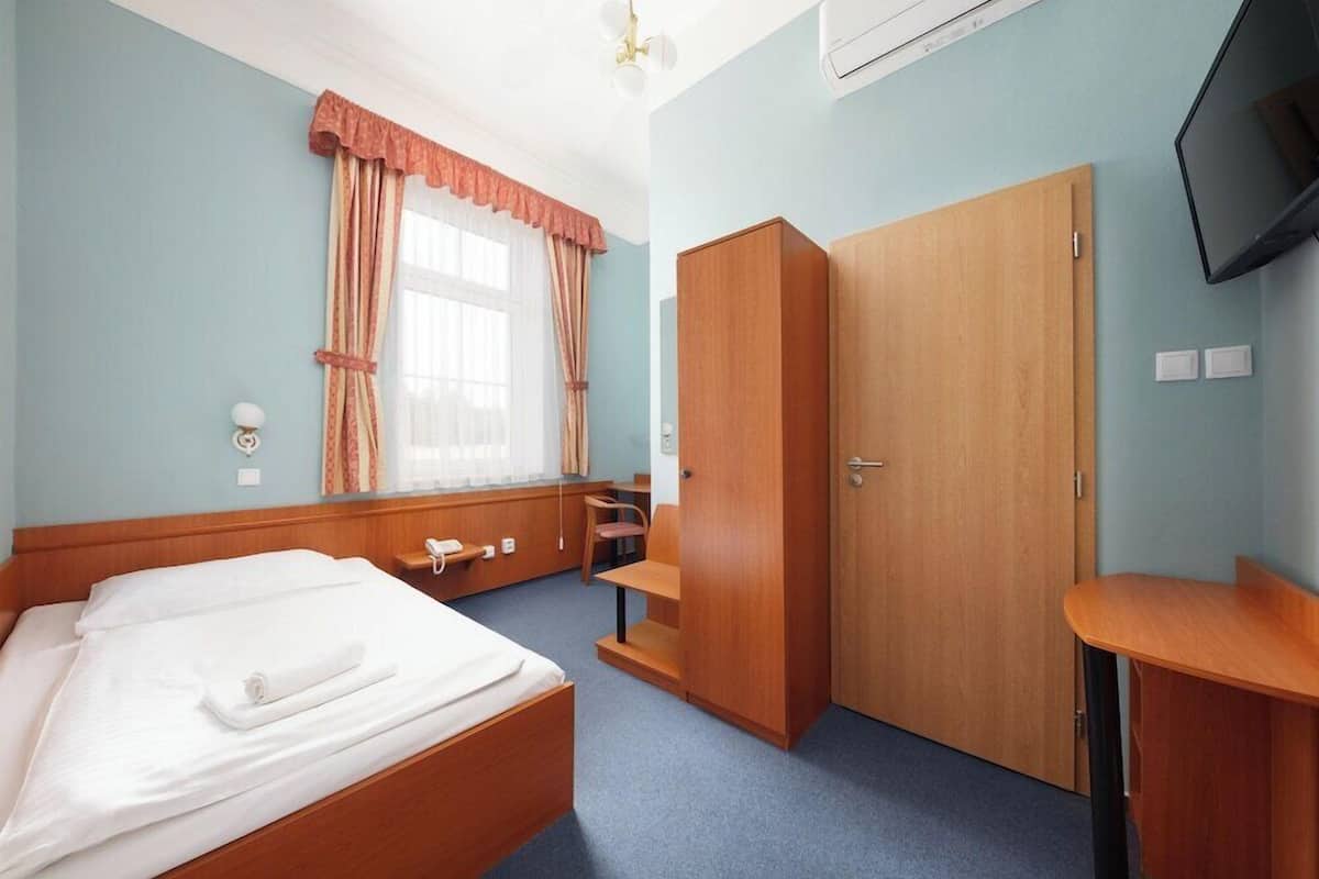 Una habitación de hotel con cama, escritorio, armario y televisión.