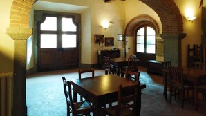 A dining area with a brick archway, wooden tables, and chairs. - Tenuta Poggio Marino (Dicomano)