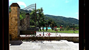 A stone pathway leading to a gated entrance with a view of a mountainous landscape and a pool. - Tenuta Poggio Marino (Dicomano)