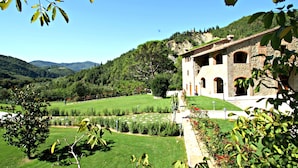 A stone building with arched windows and a well-maintained garden. - Tenuta Poggio Marino (Dicomano)