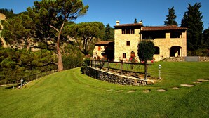 A stone building with a tiled roof, surrounded by a stone wall and a wooden fence. - Tenuta Poggio Marino (Dicomano)