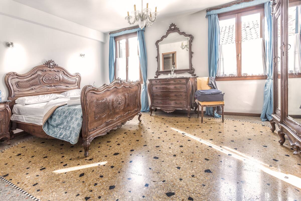 A bedroom with a large bed, a dresser, a mirror, and a chair.