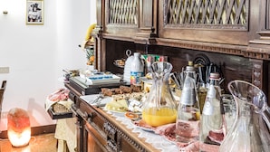 A kitchen counter with various food items, bottles, and utensils.