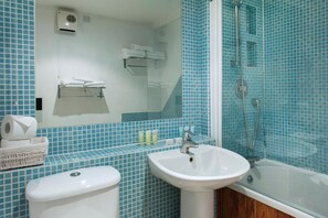 Un baño con lavamanos blanco, bañera y ducha. Hay un perchero sobre el lavamanos y un espejo sobre la bañera.