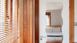 Un dormitorio con cama, puerta de madera y ventana con persianas.