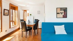 Una habitación con una mesa de comedor, sillas, un sofá azul y un cuadro en la pared.
