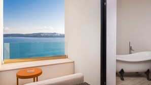 Un baño con bañera y vista a un cuerpo de agua.