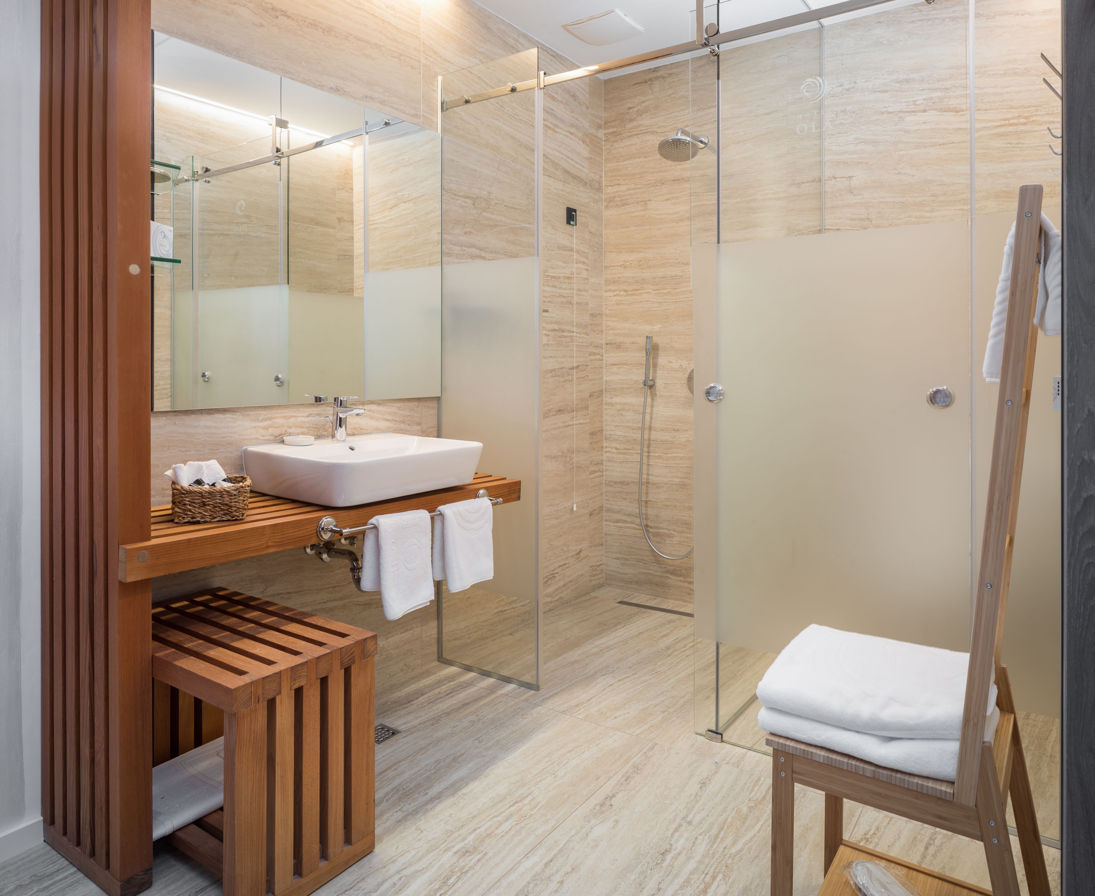 Ein modernes Badezimmer mit Duschkabine aus Glas, einem Holzlagerfeld und einem weißen Waschbecken.