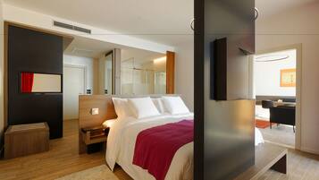 Habitación de hotel moderna con una cama grande, un televisor montado en la pared, una mesita de noche de madera y un espejo.