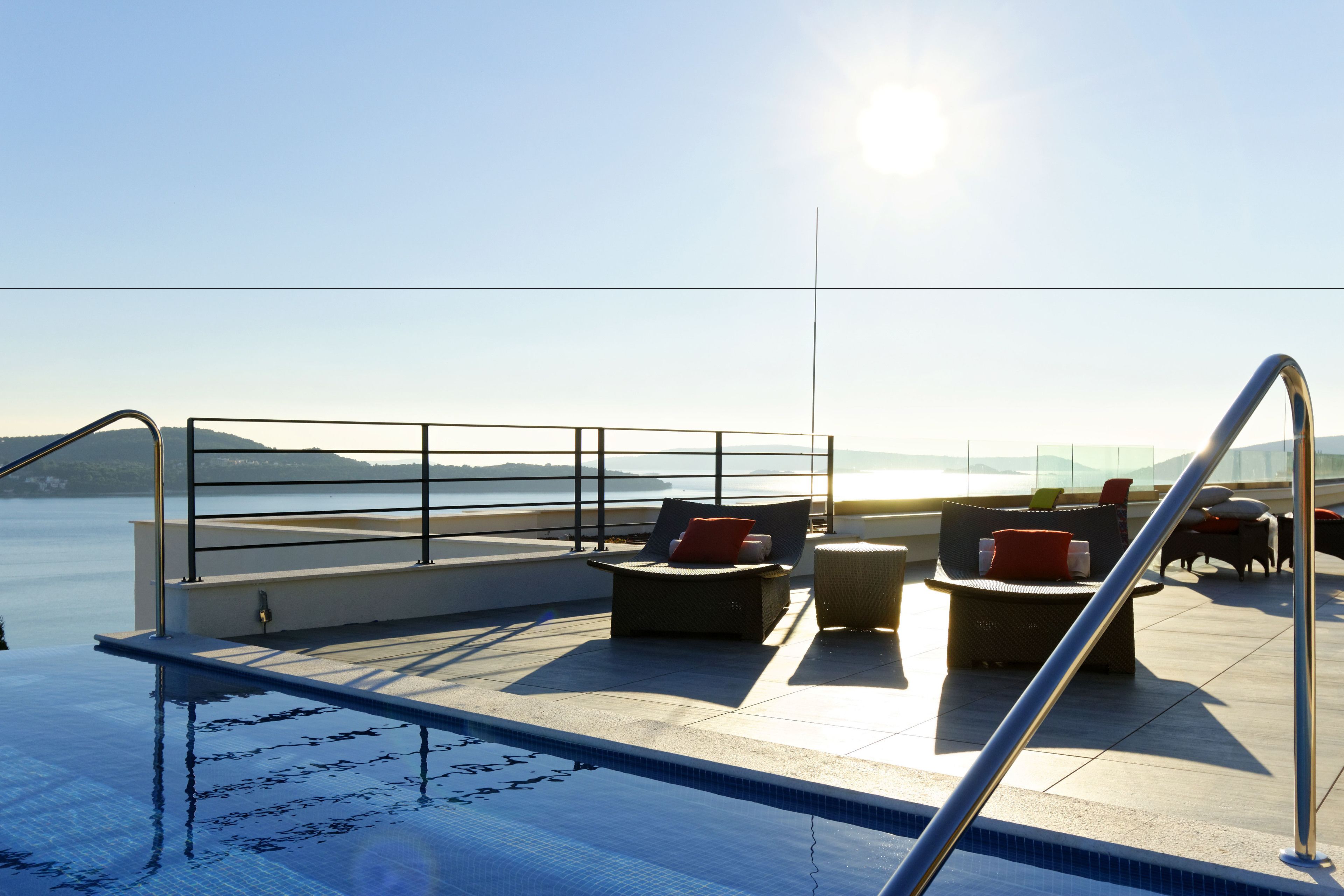 Ein Poolbereich auf dem Dach mit Liegestühlen und Blick auf den Ozean.