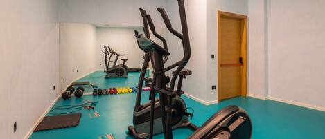 A gym with various exercise equipment, including treadmills and weights, on a blue floor.